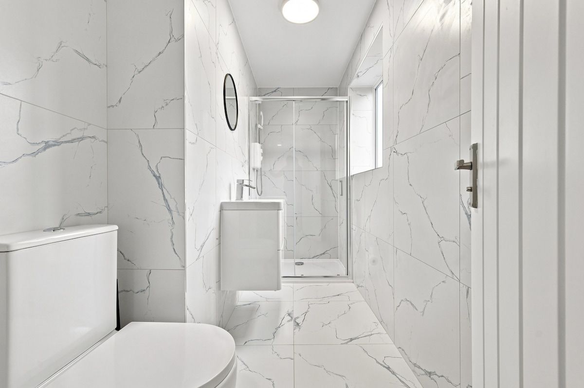Une salle de bain moderne équipée de toilettes, d’un lavabo et d’une zone douche.