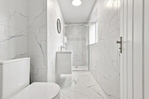 Een moderne badkamer met toilet, wastafel en douchehoek.