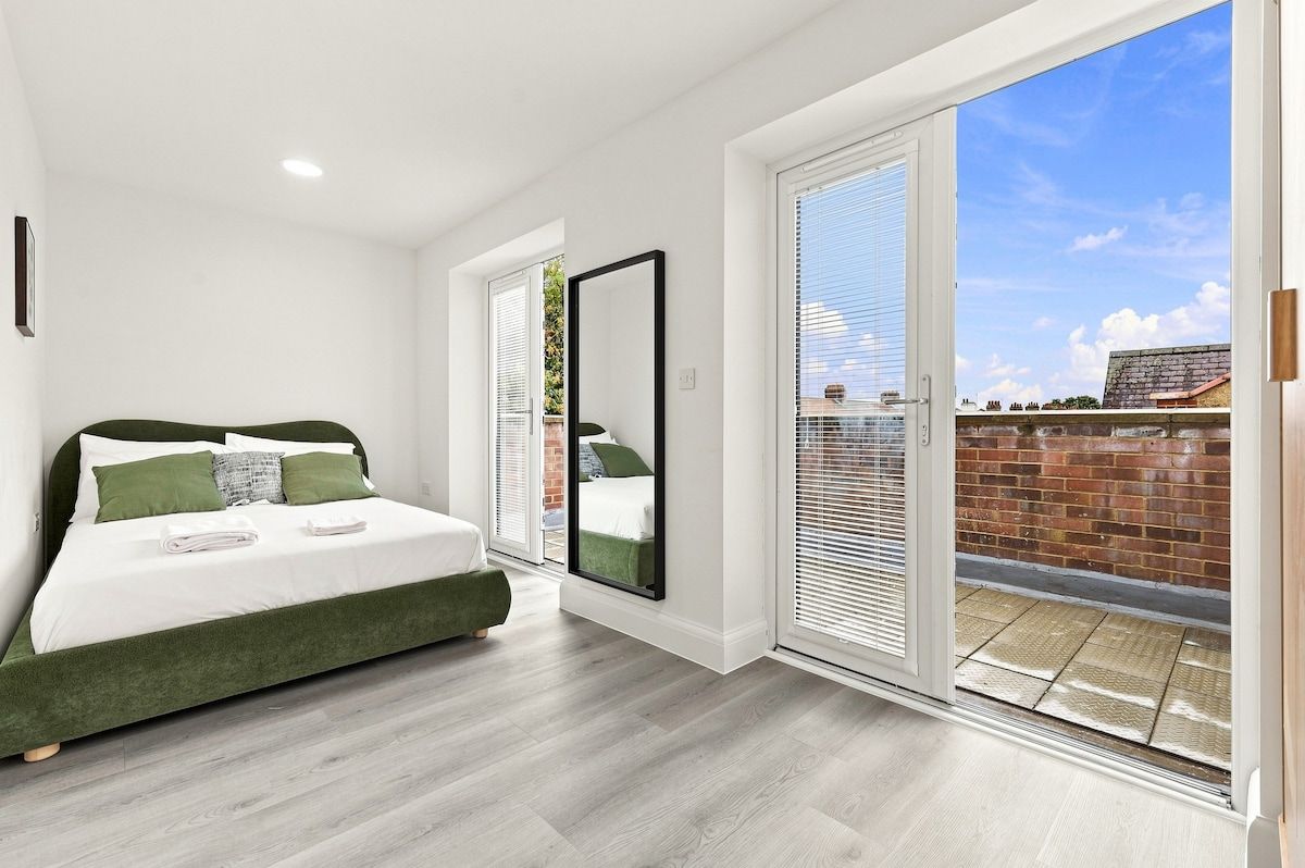 Une chambre à coucher comprenant un lit, un grand miroir et une porte-fenêtre coulissante donnant sur un espace extérieur.