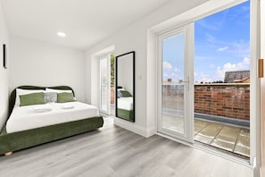 Een slaapkamer met een bed, een grote spiegel en een schuifdeur die uitkomt op een buitenruimte.