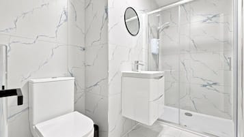 Ein modernes Badezimmer mit Toilette, Waschbecken und einer Duschkabine.