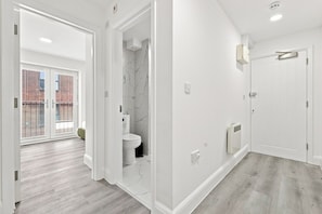 Een moderne badkamer met toilet, douche en witte wanden.