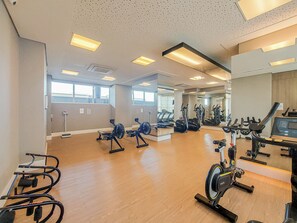 Ein Fitnessraum mit Trainingsgeräten, großen Fenstern und Holzboden.