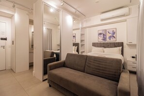 Ein modernes Schlafzimmer mit Bett, Sofa, Nachttisch, Klimaanlage und Spiegel.