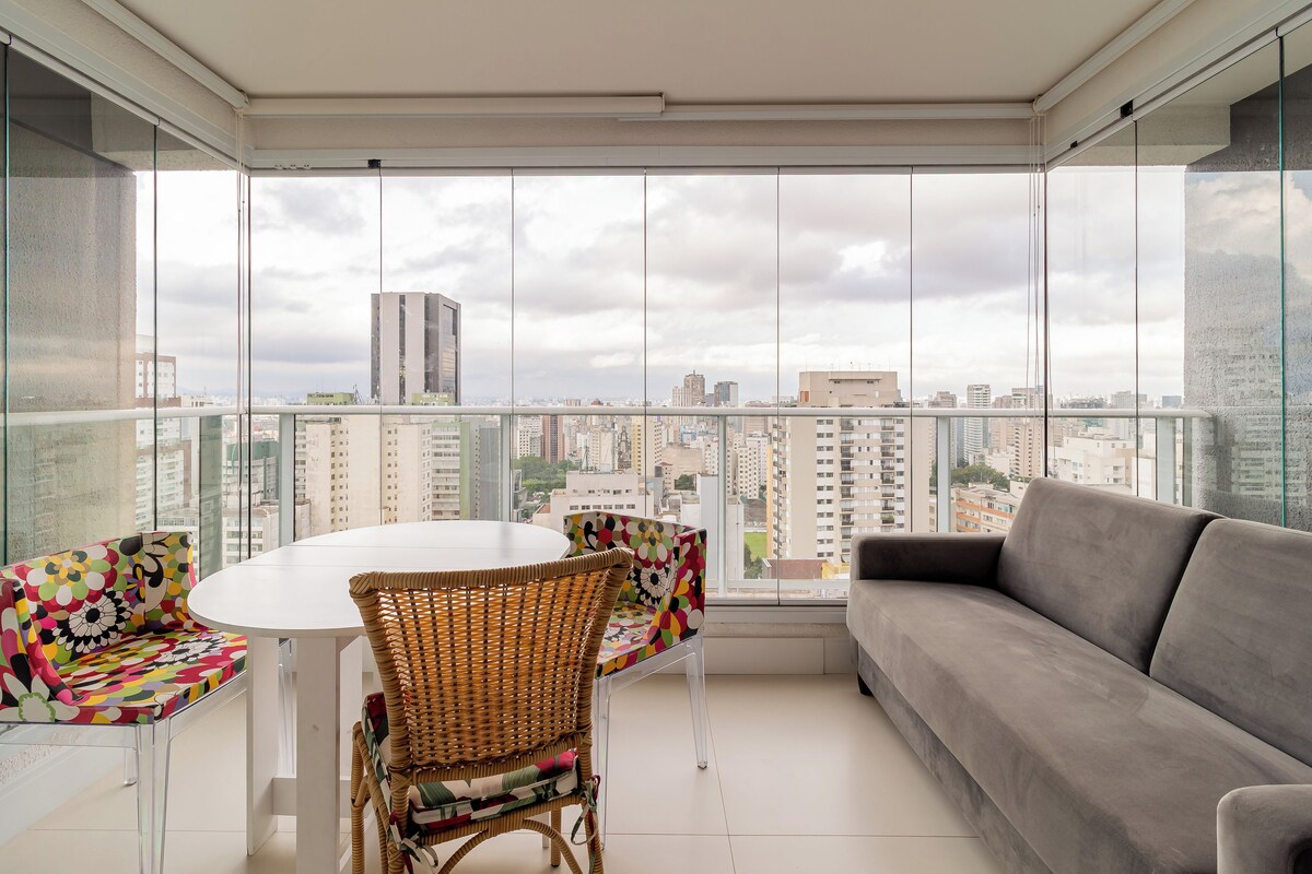 Ein Balkon mit einem weißen Tisch, Korbstühlen und einem grauen Sofa.