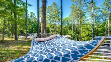 A hammock in a forested area with a clear sky.