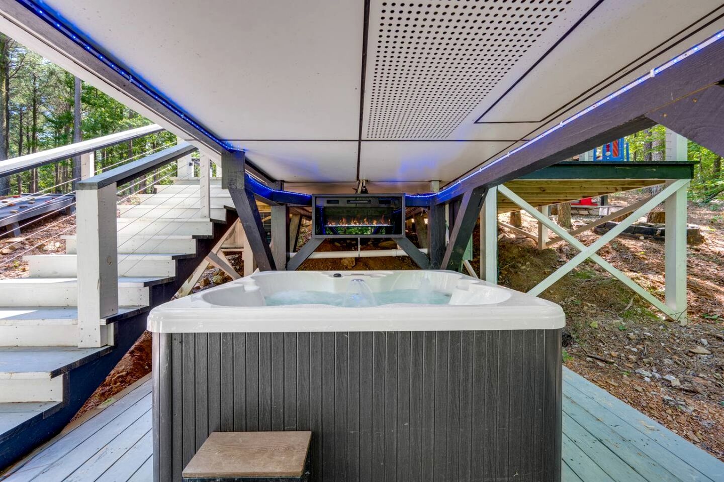 A hot tub on a wooden deck with a view of a forested area.