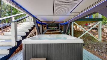 A hot tub on a wooden deck with a view of a forested area.