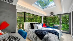Un dormitorio moderno con tragaluz, una cama grande, un tablero de ajedrez y vistas a zonas verdes.