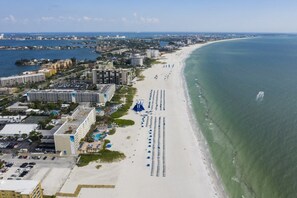 Ein Hotel an der Küste mit Blick auf den Strand, mehreren Schwimmbecken und einem Parkplatz.