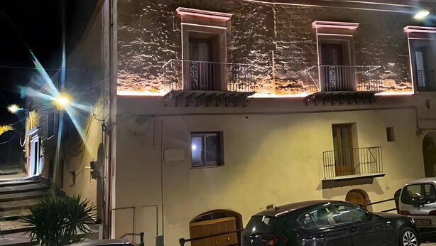 Un immeuble doté de plusieurs balcons, d’une petite fenêtre et d’une voiture garée devant.