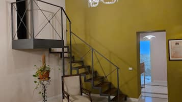 Una escalera con barandilla de metal, un candelabro, una silla y una planta en maceta.