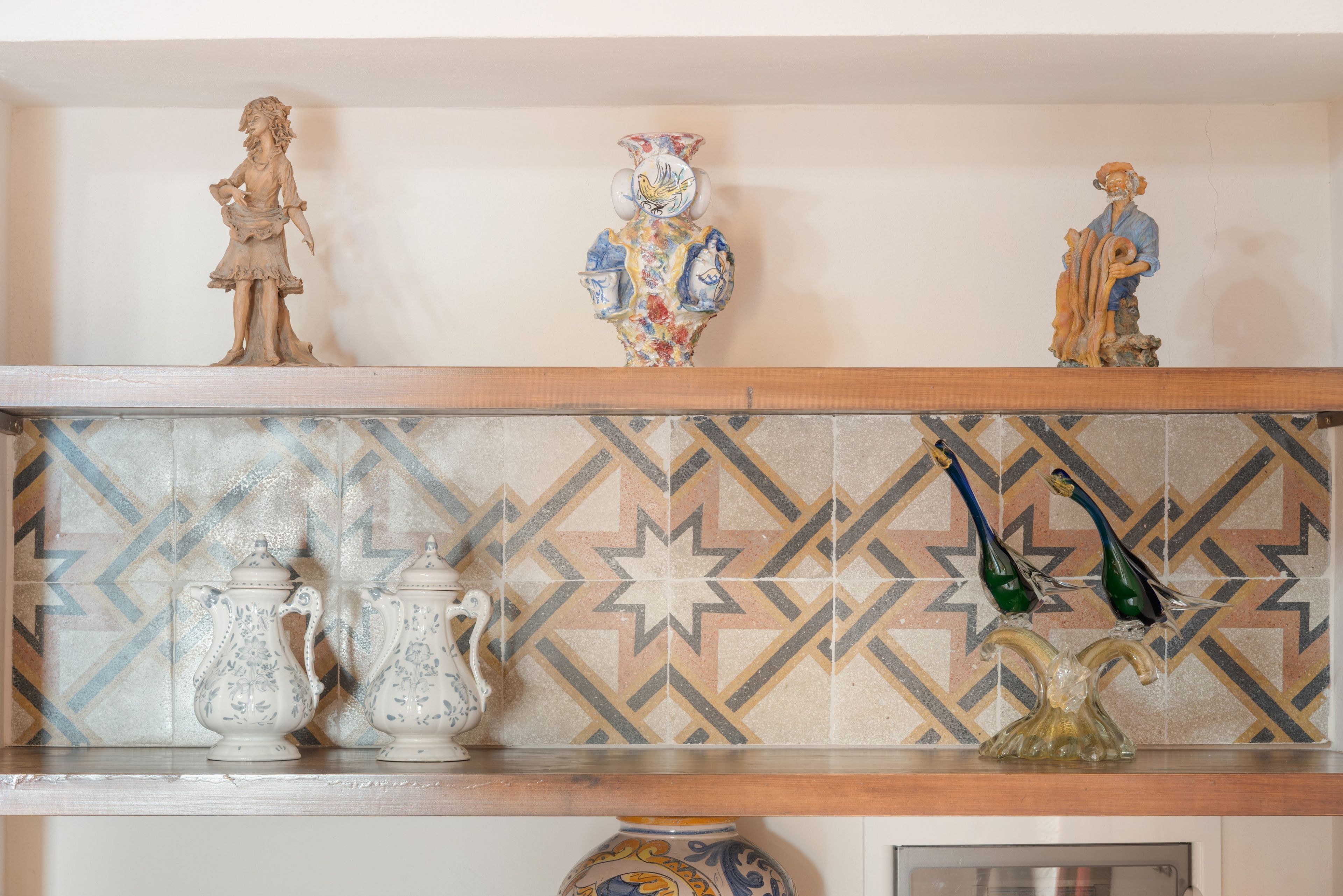 Una mensola con diversi oggetti in ceramica, tra cui una figurina, un vaso e due brocche.