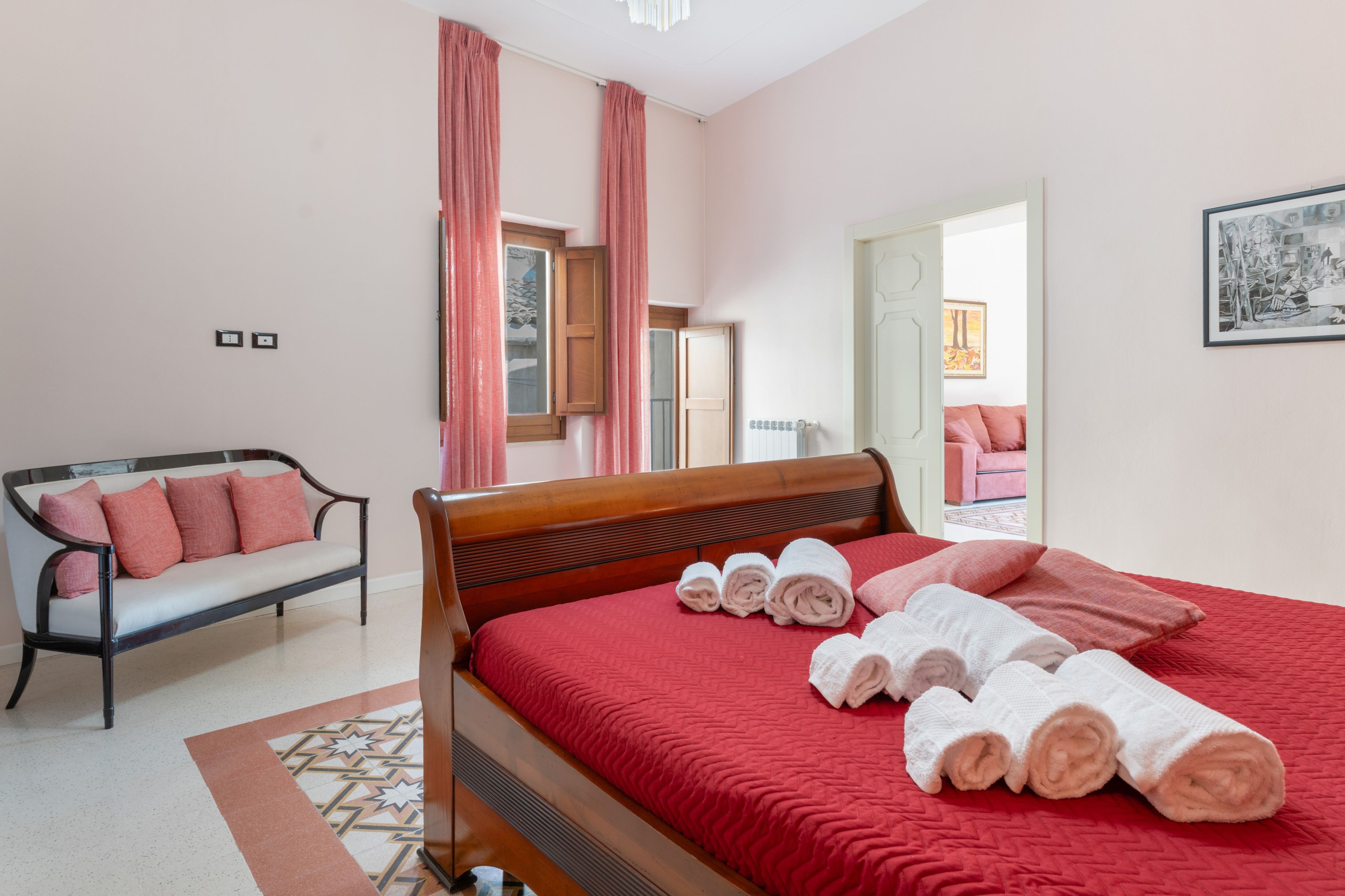 Una camera da letto con un letto di legno, una panca con cuscini, un termosifone e un quadro appeso al muro.
