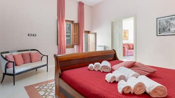Una camera da letto con un letto di legno, una panca con cuscini, un termosifone e un quadro appeso al muro.