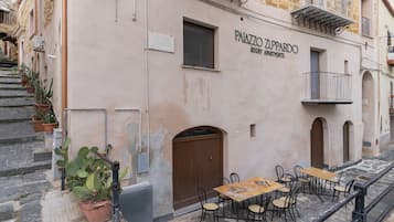 Un edificio con un cartel que dice 'PALAZZO ZUPPARDO LUXURY APARTMENTS' y un área de estar al aire libre con mesas y sillas.