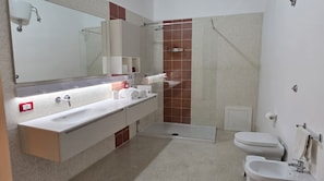 Ein modernes Badezimmer mit großem Spiegel, Waschbecken, Dusche und Toilette.