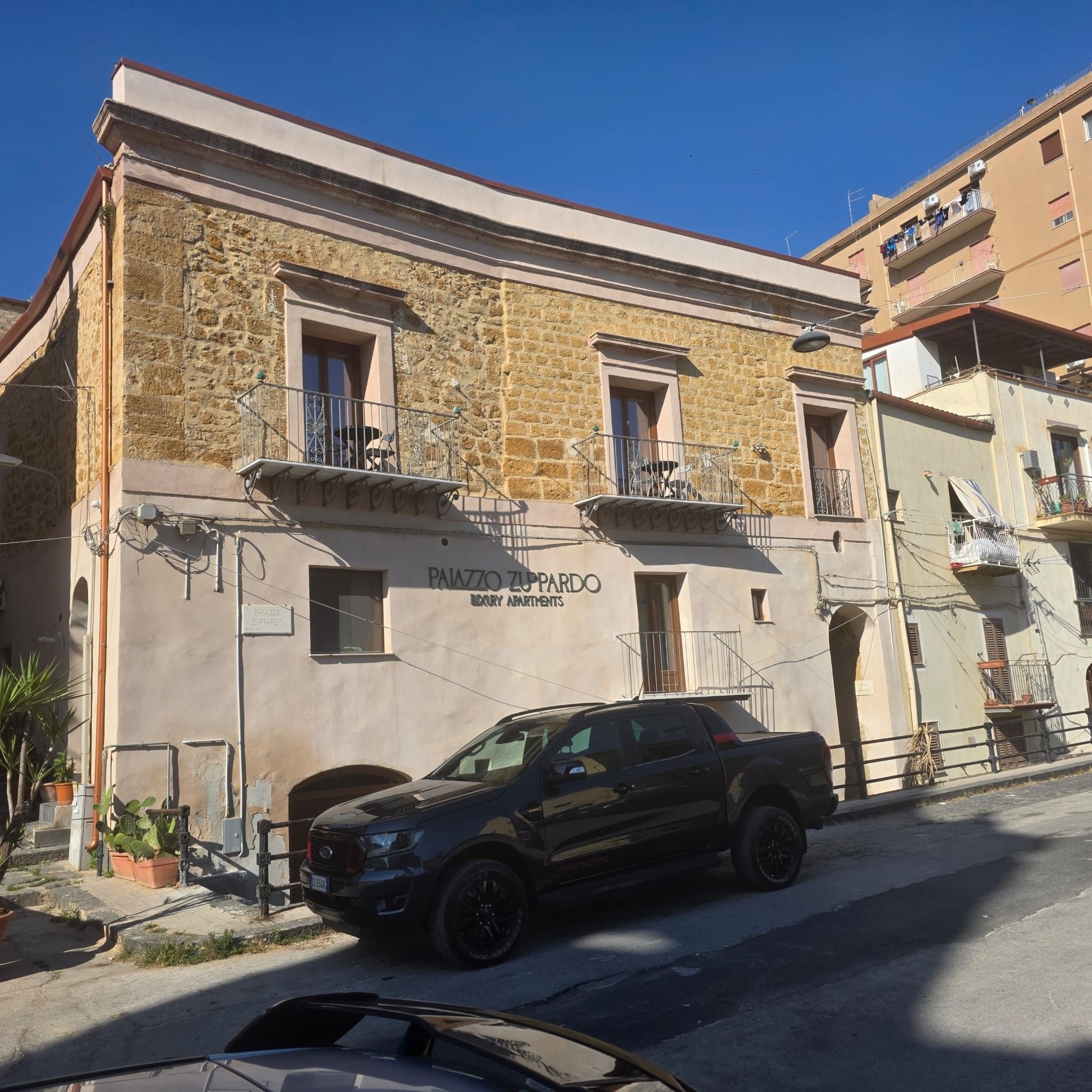 Un immeuble à la façade en pierre, doté de balcons et d’une enseigne indiquant qu’il s’agit d’un complexe d’appartements de luxe.