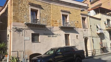 Un immeuble à la façade en pierre, doté de balcons et d’une enseigne indiquant qu’il s’agit d’un complexe d’appartements de luxe.