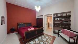 Une chambre à coucher comprenant un lit, un canapé, un tapis à motifs et une étagère décorative.