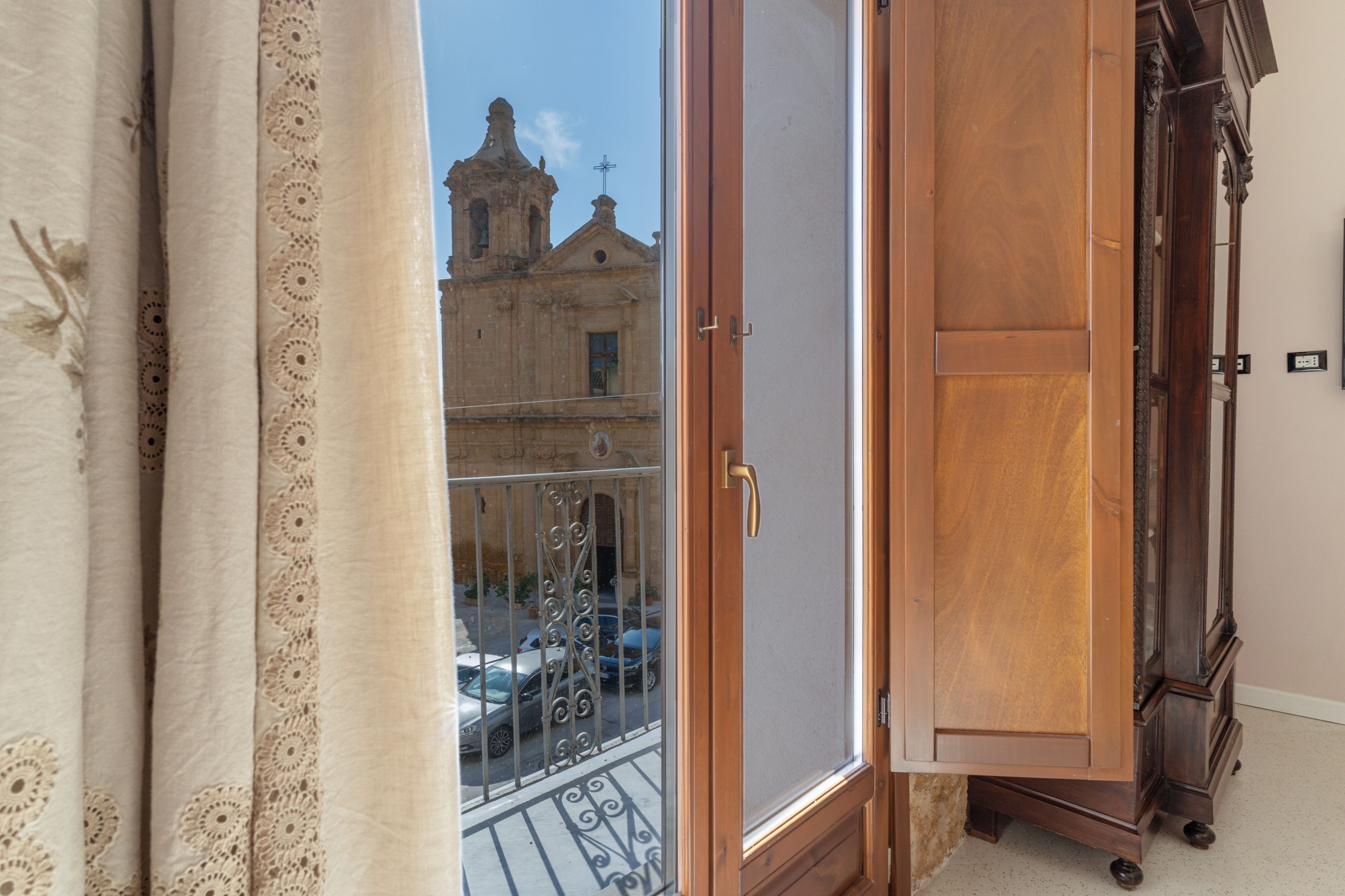 Una habitación con vista a un edificio a través de una ventana con cortinas de encaje.