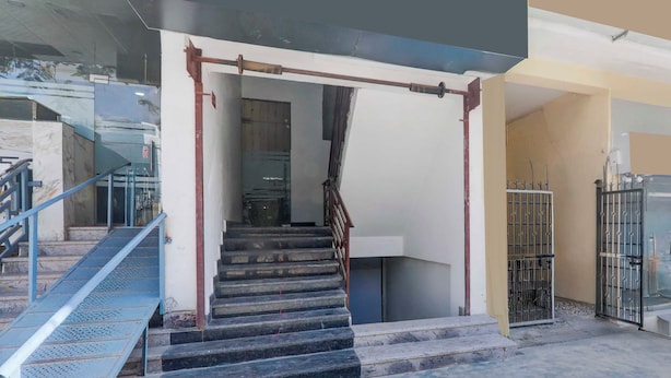 Una escalera conduce a un piso superior, con barandilla metálica y puerta de cristal al final.