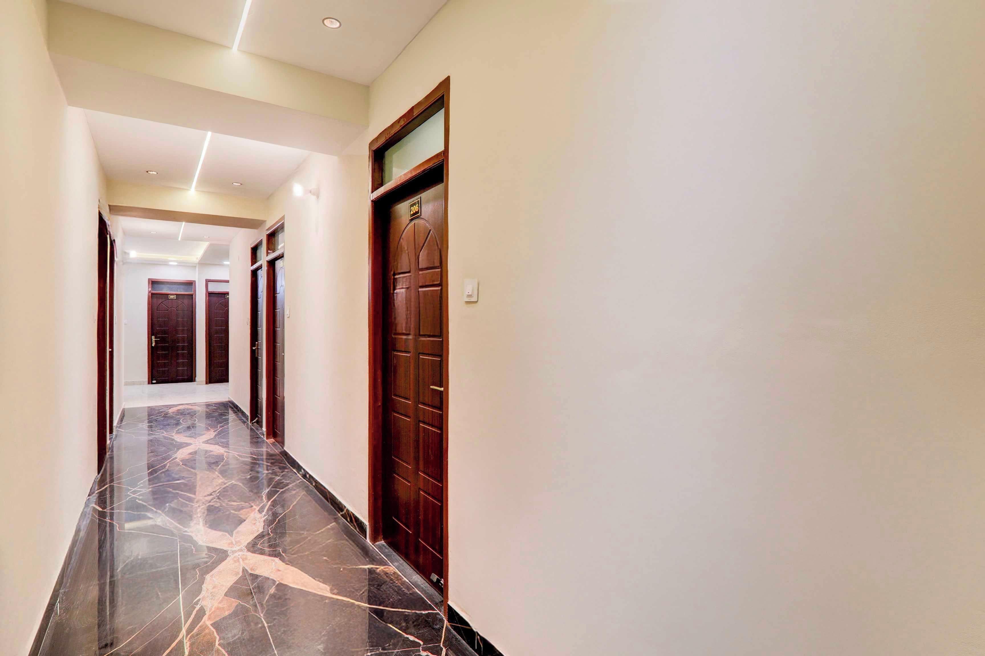 A hallway with marble flooring, wooden doors, and recessed lighting.