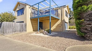 A two-story house with a covered patio area and a wooden fence. - Beach Road Retreat  Pet Friendly Walk to Beach (Torquay)