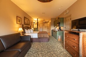 Une chambre d’hôtel comprenant un lit, un canapé, une télévision, une kitchenette et une salle de bain.