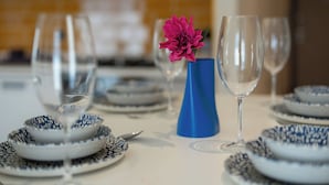 A dining table set with blue and white patterned plates, a blue vase with a pink flower, and clear wine glasses. - Botanica Houses (Muratpaşa)