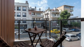A balcony with a wooden table and benches, overlooking a street with cars and buildings. - Botanica Houses (Muratpaşa)