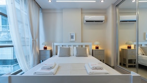 A hotel room with a bed, bedside tables, an air conditioning unit, and a large mirror. - Botanica Houses (Muratpaşa)