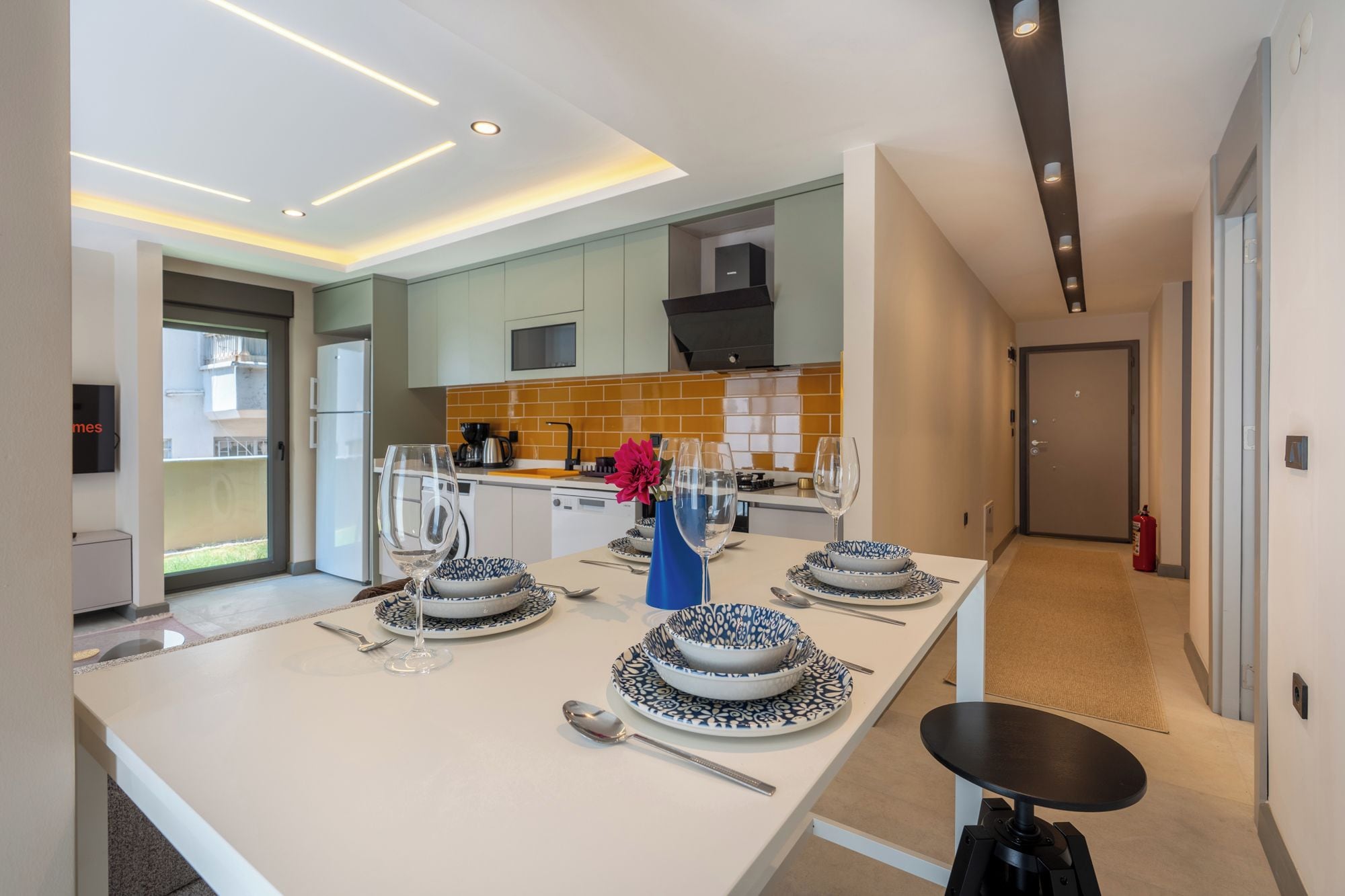 Cocina moderna con comedor, que cuenta con una isla central con una mesa preparada para cuatro personas, un microondas y una estufa.