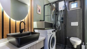 A modern bathroom with a black sink, a washing machine, a shower, and a toilet. - Botanica Houses (Muratpaşa)