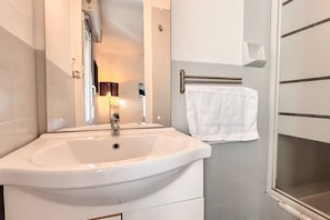 Een badkamer met een witte wastafel, een handdoekhouder en een douche.