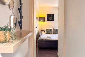 Een hotelkamer met een bed, nachtkastje en een wandlamp.