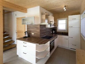 A compact kitchen with wooden cabinets, a built-in oven, and a window. - One-bedroom Cabin (Sankt Georgen am Kreischberg)
