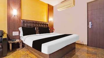 Una habitación de hotel con cama, mesita de noche, lámpara y equipo de aire acondicionado.