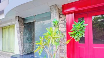 Un edificio con una puerta roja, una verde y una azul. Hay macetas con plantas delante de las puertas.