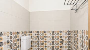 Une petite salle de bain moderne, équipée de toilettes, d’une douche et d’un porte-serviettes.