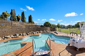 A swimming pool with a 3-foot depth marker, surrounded by a brick wall, a grassy area, and trees.