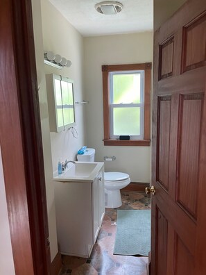 Et badeværelse med toilet, vask og vindue.