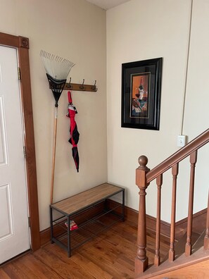 A wooden bench, a rake, and a framed picture on a wall.