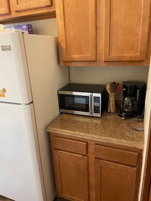 A kitchen with a white refrigerator, a microwave, and a coffee maker on the counter.