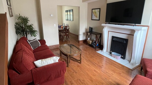 Una sala de estar con chimenea, televisión y sofás rojos.