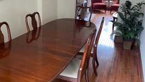Un área de comedor con una gran mesa de madera, sillas y un televisor sobre un mueble.