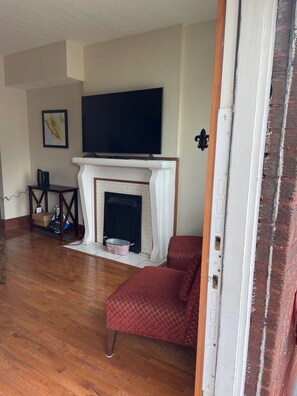 A living room with a fireplace, a television, and a red armchair.
