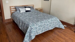 Un dormitorio con cama de madera, una mesita de noche y un cuadro en la pared.