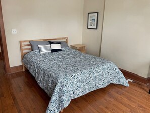 Et soveværelse med en træseng, et natbord og et billede hængt på væggen.