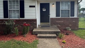 A single-story house with a front door, a small porch, and a brick foundation. - Soft Haven/ Warm and Cozy Getaway (Clarksville)